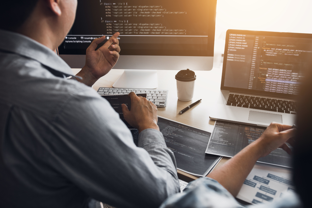 兩名軟件開發(fā)人員正在使用計算機(jī)與辦公桌上的合作伙伴一起工作